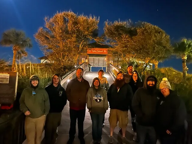 A group of people pose for a photo at night.
