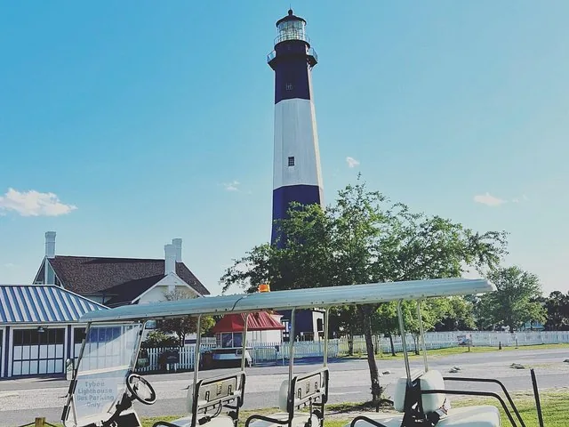 Ein hoher schwarz-weißer Leuchtturm steht hinter einem Gebäude.