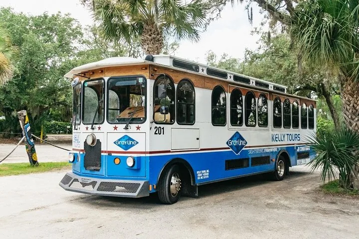 Ein blau-weißer Sightseeing-Bus parkt in der Nähe von Bäumen.